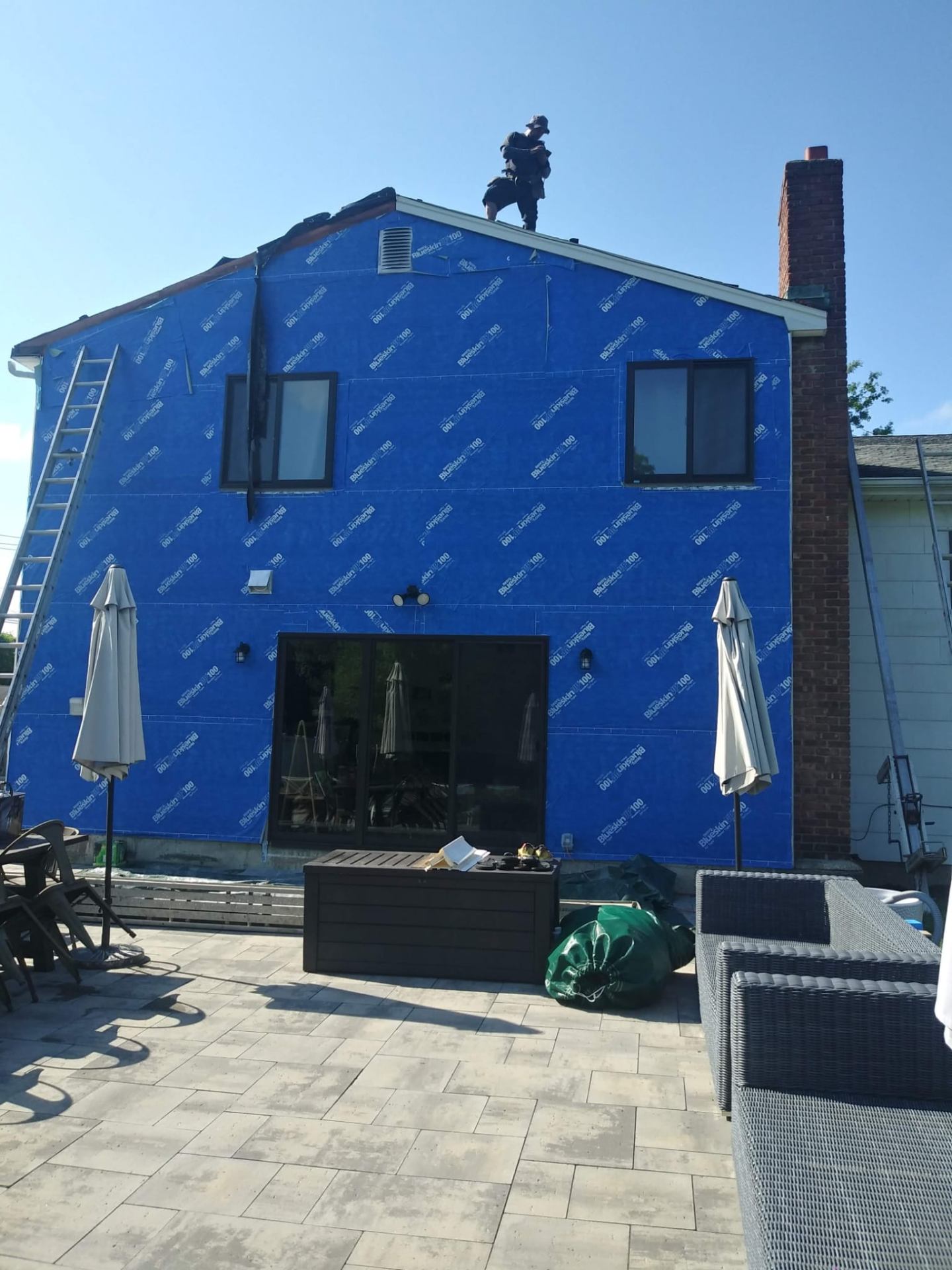 Roofer at a gable peak installing a full weather barrier on a home exterior