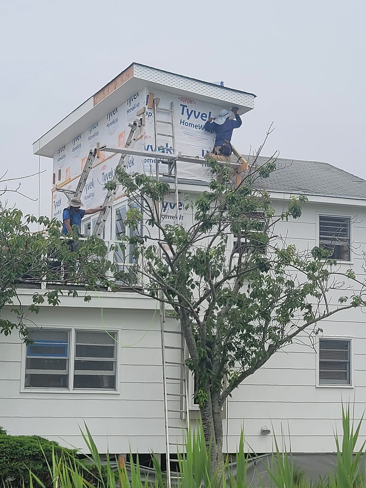 Crew installing house wrap on a second-story dormer addition